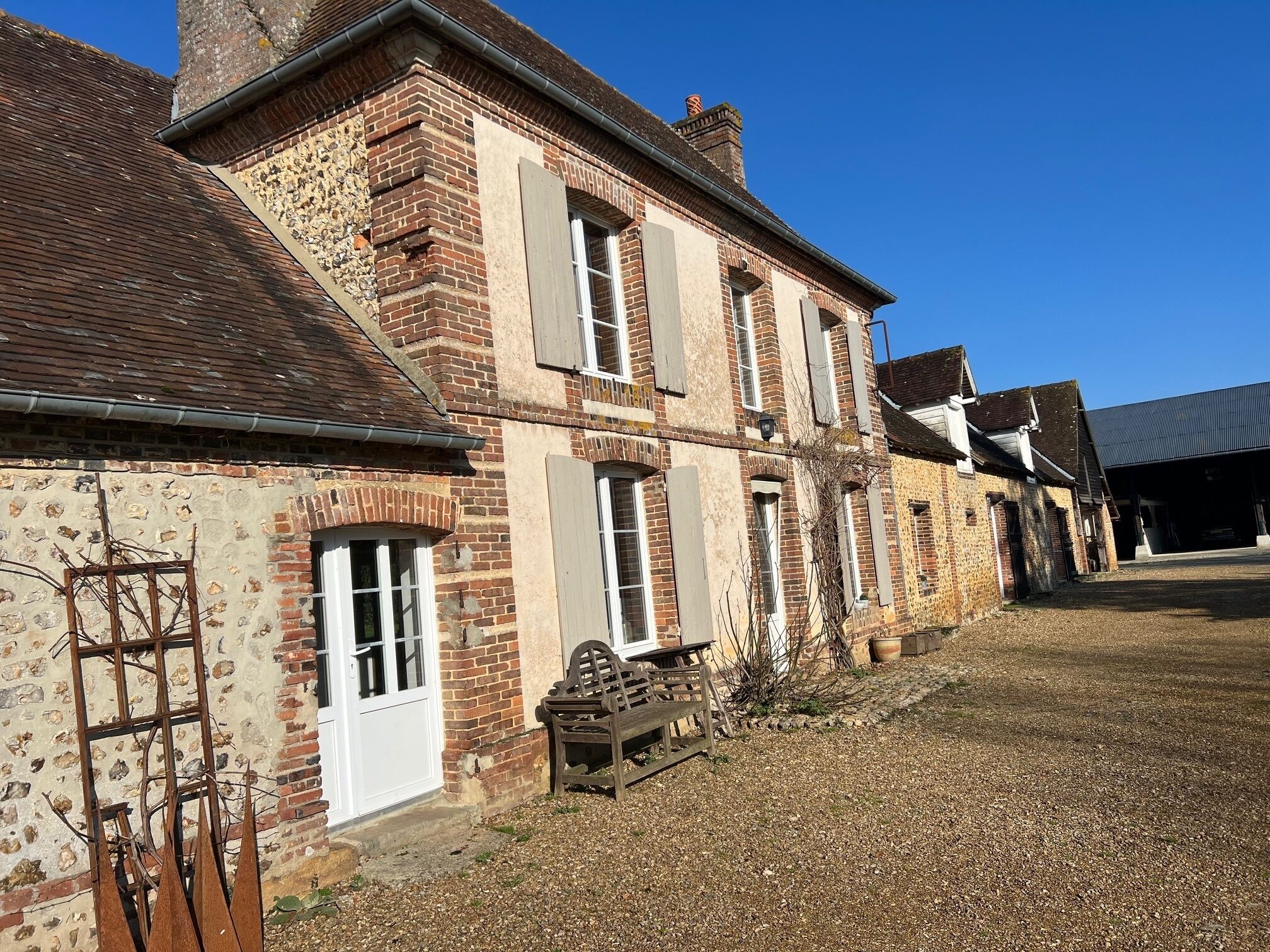A traditional brick building with multiple windows and a gravel courtyard.