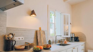 A kitchen with a wooden cutting board, a bowl of fruit, a coffee maker, and a sink. - Villa Phoenix - Ancient and modern charm (La Couarde sur mer)