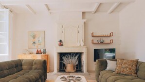 A living room with a fireplace, two sofas, a TV, and a painting on the wall. - Villa Phoenix - Ancient and modern charm (La Couarde sur mer)