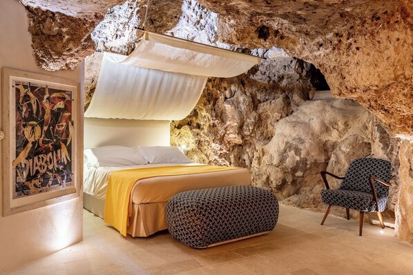 Una camera da letto con un letto, una sedia e un muro simile a una grotta.