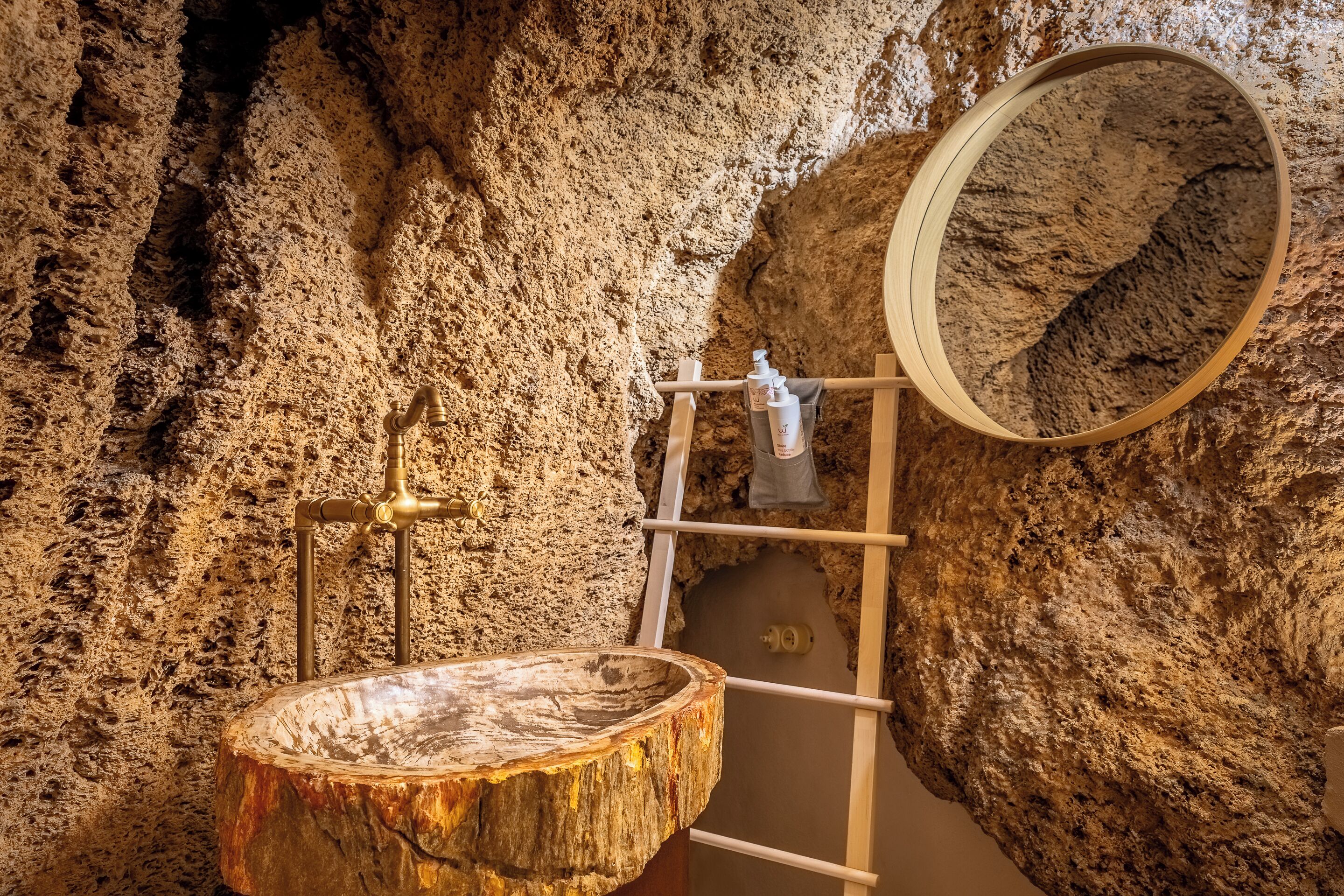 Un bagno rustico con una vasca in legno, un rubinetto in ottone e uno specchio con cornice in legno.