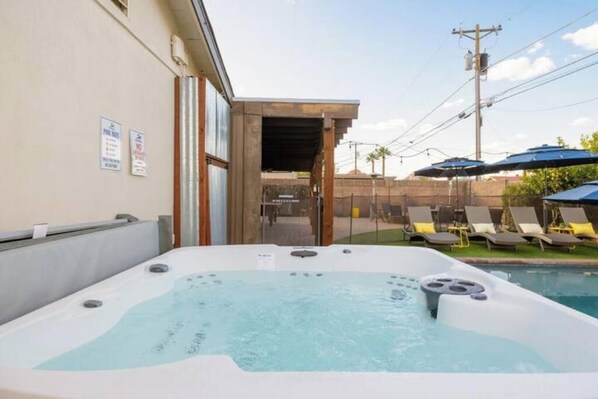 A hot tub with a pool in the background, a wooden deck, and lounge chairs. - Rancho Relaxo: Dog friendly! Enjoy heated pool, hot tub, pool table, outdoor TV! (Scottsdale)