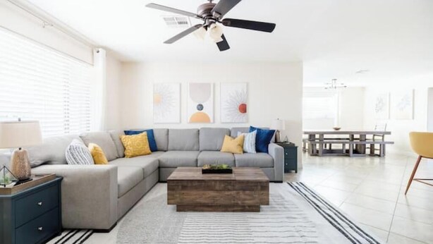 A modern living room with a grey sectional sofa, a wooden coffee table, and a ceiling fan.