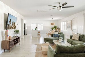 A modern living room with a sofa set, a dining area, and a kitchen in the background.