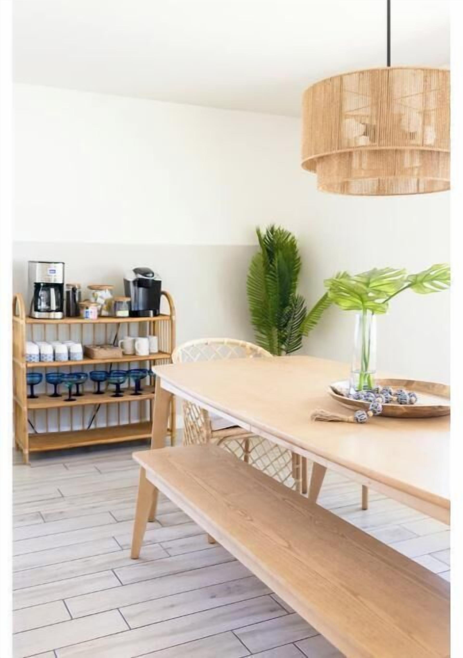 A dining area with a wooden table, bench, and hanging light fixture.
