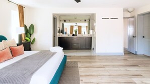 A modern bedroom with a bed, a ceiling fan, a nightstand, and a large window.