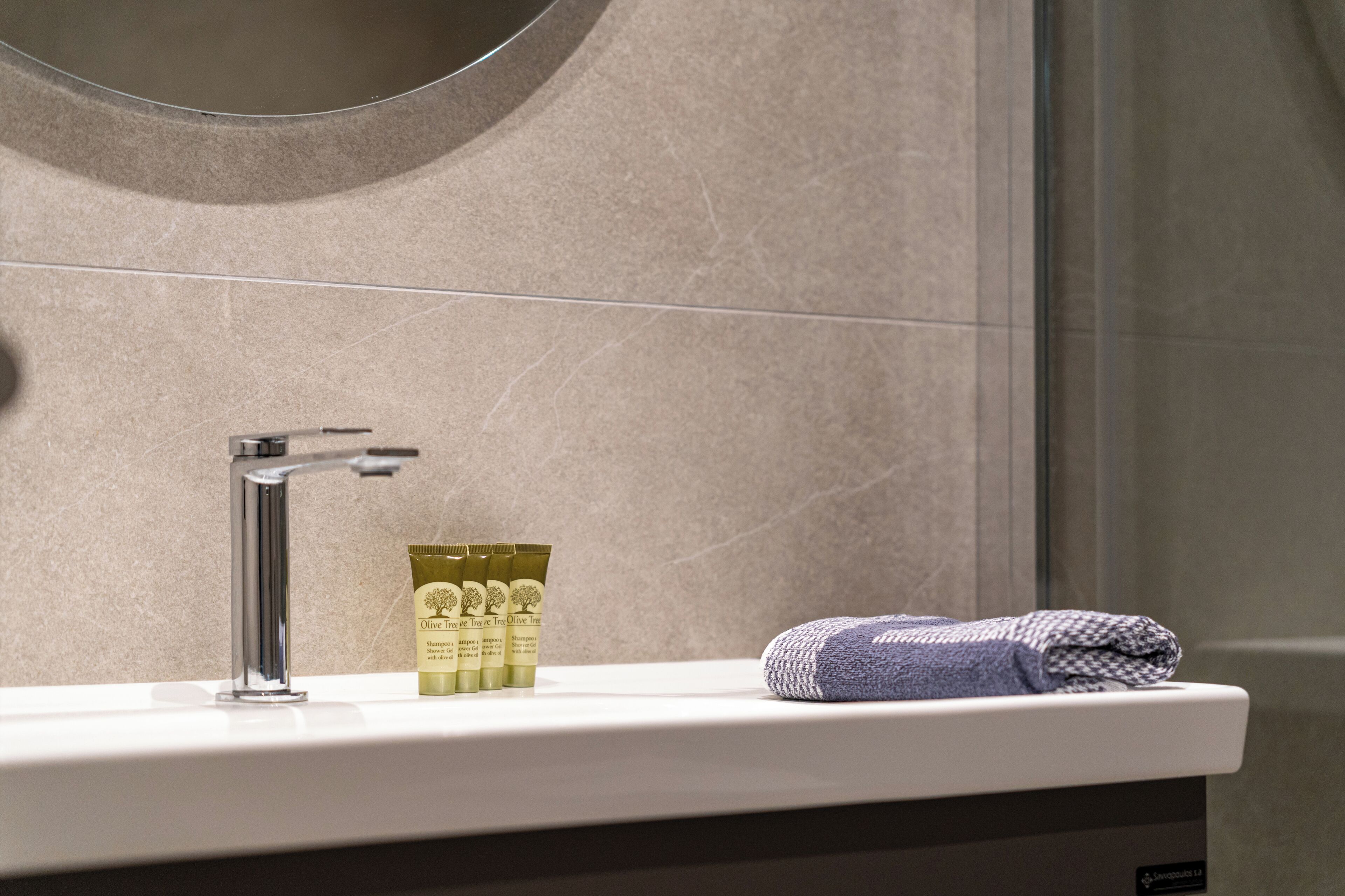 A bathroom with a white sink, a chrome faucet, and a towel on the counter.
