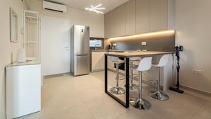 A modern kitchen with a central island, bar stools, and a built-in dishwasher.
