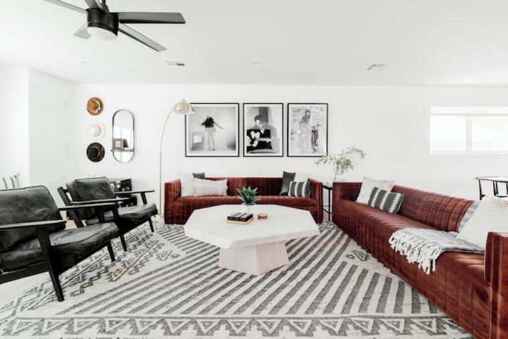 A modern living room with a red sofa, black chairs, a white coffee table, and patterned rugs.