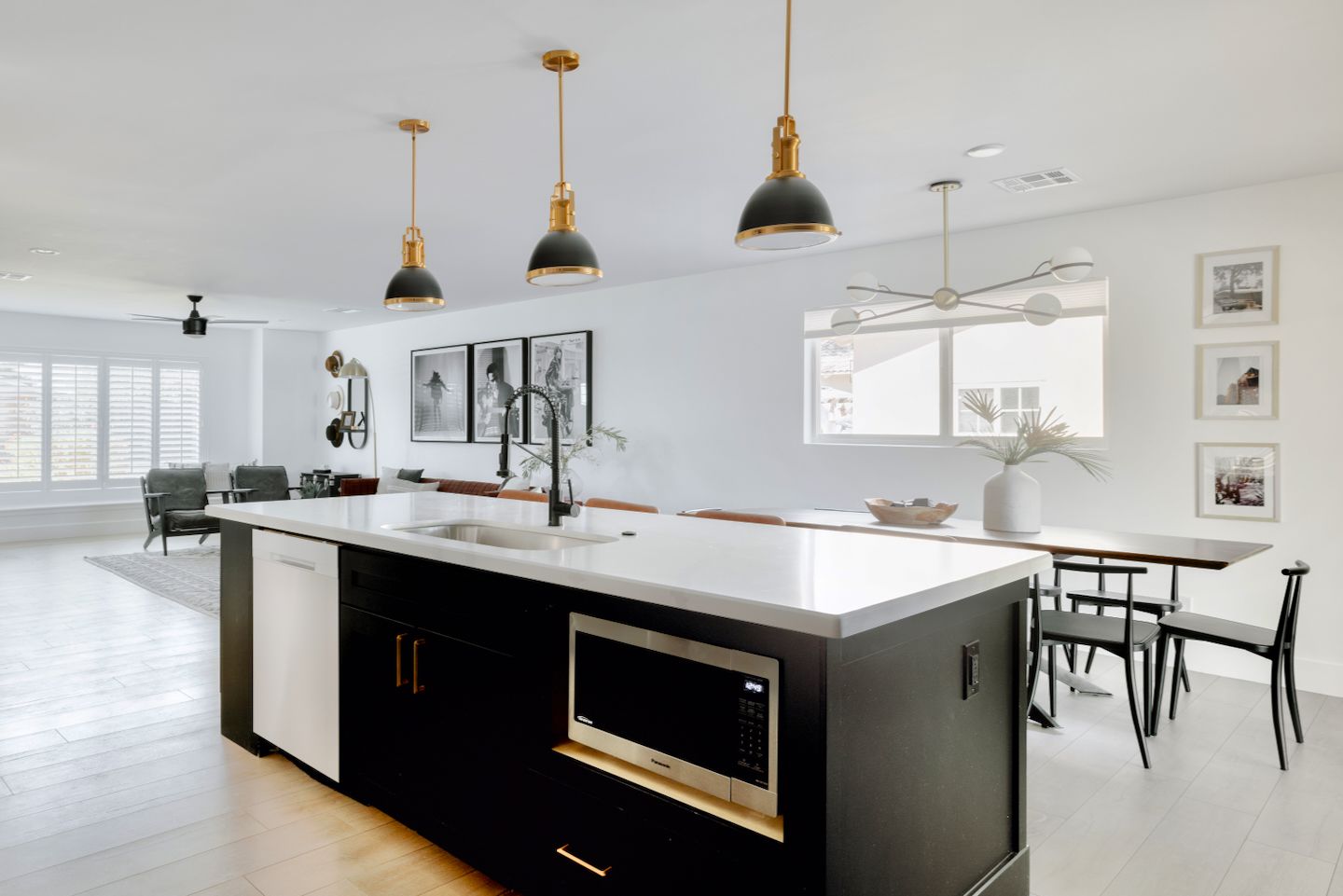 A modern kitchen with a central island, pendant lighting, and a dining area with a table and chairs.