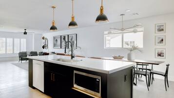 A modern kitchen with a central island, pendant lighting, and a dining area with a table and chairs.