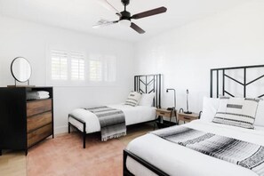 Un dormitorio con una cama, un aparador, una mesita de noche, una lámpara y un ventilador de techo.