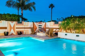 Una piscina con sillones de descanso y un muro con diseño.