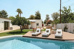 Una piscina con sillones de descanso y una terraza de madera.