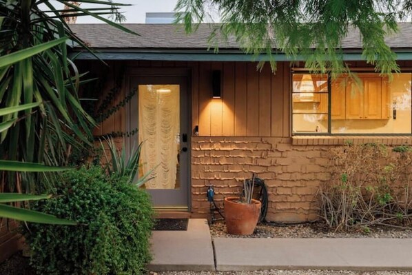Una casa con fachada de piedra, puerta de madera y una ventana pequeña.