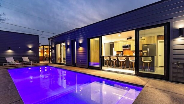 Una casa moderna con piscina, zona de bar y cocina visible a través de puertas de cristal.