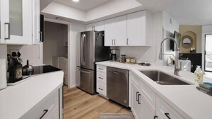 A modern kitchen with white cabinets, stainless steel appliances, and a large sink. - Escape 48! Heated Pool, Hot Tub, Fitness Center, walk to Coffee, Grocery (Phoenix)
