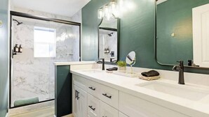 A modern bathroom with a white vanity, a large mirror, and a shower area.
