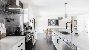 Une cuisine moderne avec des meubles blancs, des appareils en acier inoxydable et un îlot central.