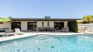 Une maison moderne dotée d’une piscine, d’un espace salon extérieur et d’un patio couvert.