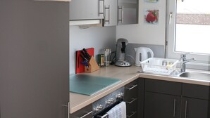 Una cocina equipada con microondas, cafetera y lavabo.