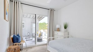 Un dormitorio con cama, una silla, una mesita y una mesita de noche.