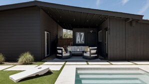 Una casa moderna con un porche cubierto, una piscina y un letrero grande con la letra 'AZ'.