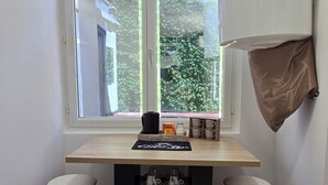 A small kitchen with a window, two stools, a black rug, and a white ceiling light. - Sweet Escape. T1 BIS ROMANTIC (Bourg-lès-Valence)