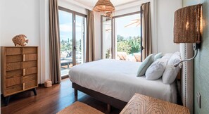 Une chambre avec un grand lit, une commode en bois et une vue sur l’extérieur.