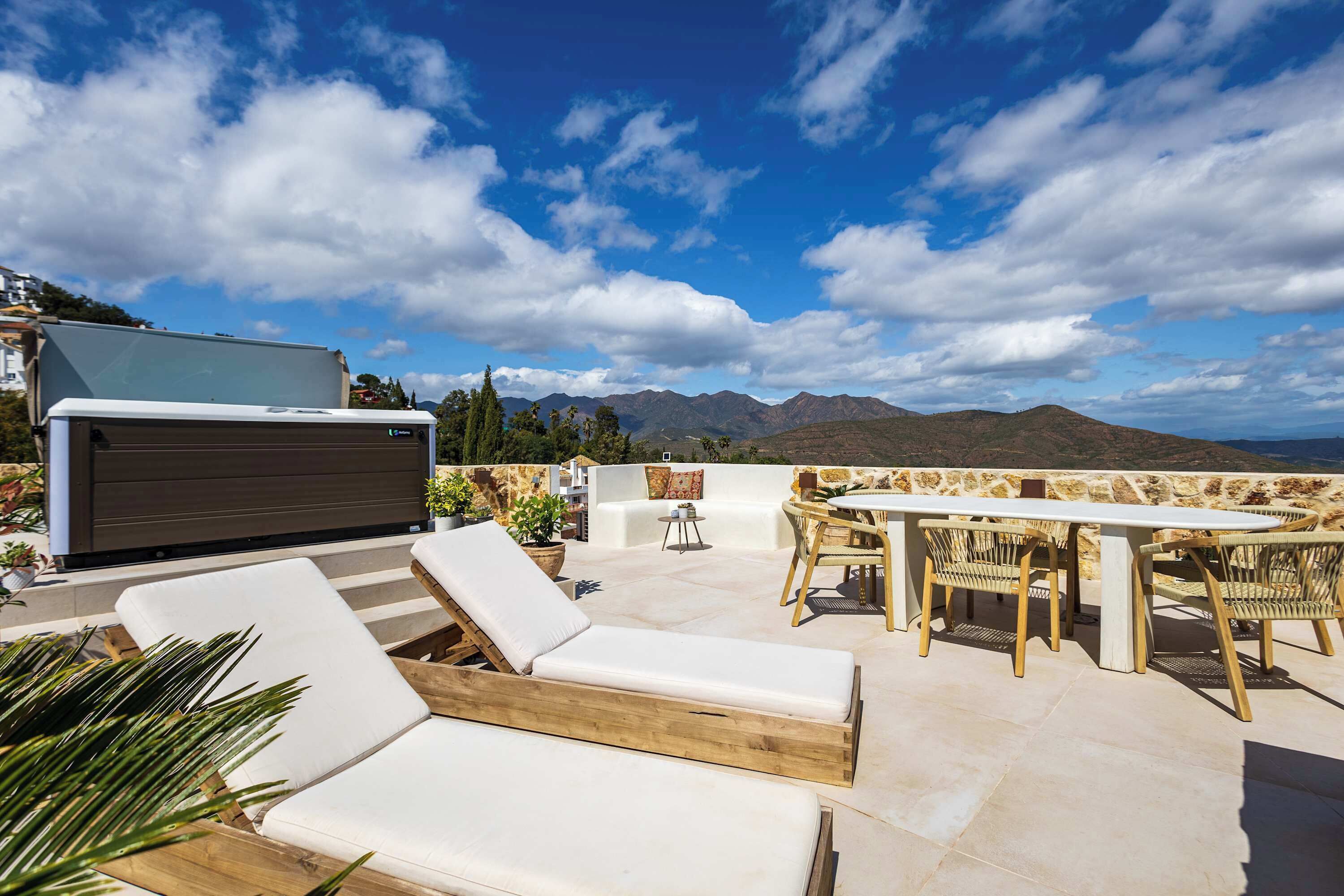 A patio with lounge chairs, a table, and a grill.