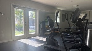 A home gym with treadmills and exercise equipment, large sliding glass doors leading to a backyard, and a ceiling fan. - Turtle cove: Perfect Cozy Oasis in SWFL with Pool, Hot Tub & More! (Fort Myers)