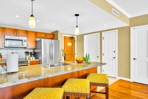 Una cocina con armarios de madera, un refrigerador de acero inoxidable, un microondas y una encimera de granito.