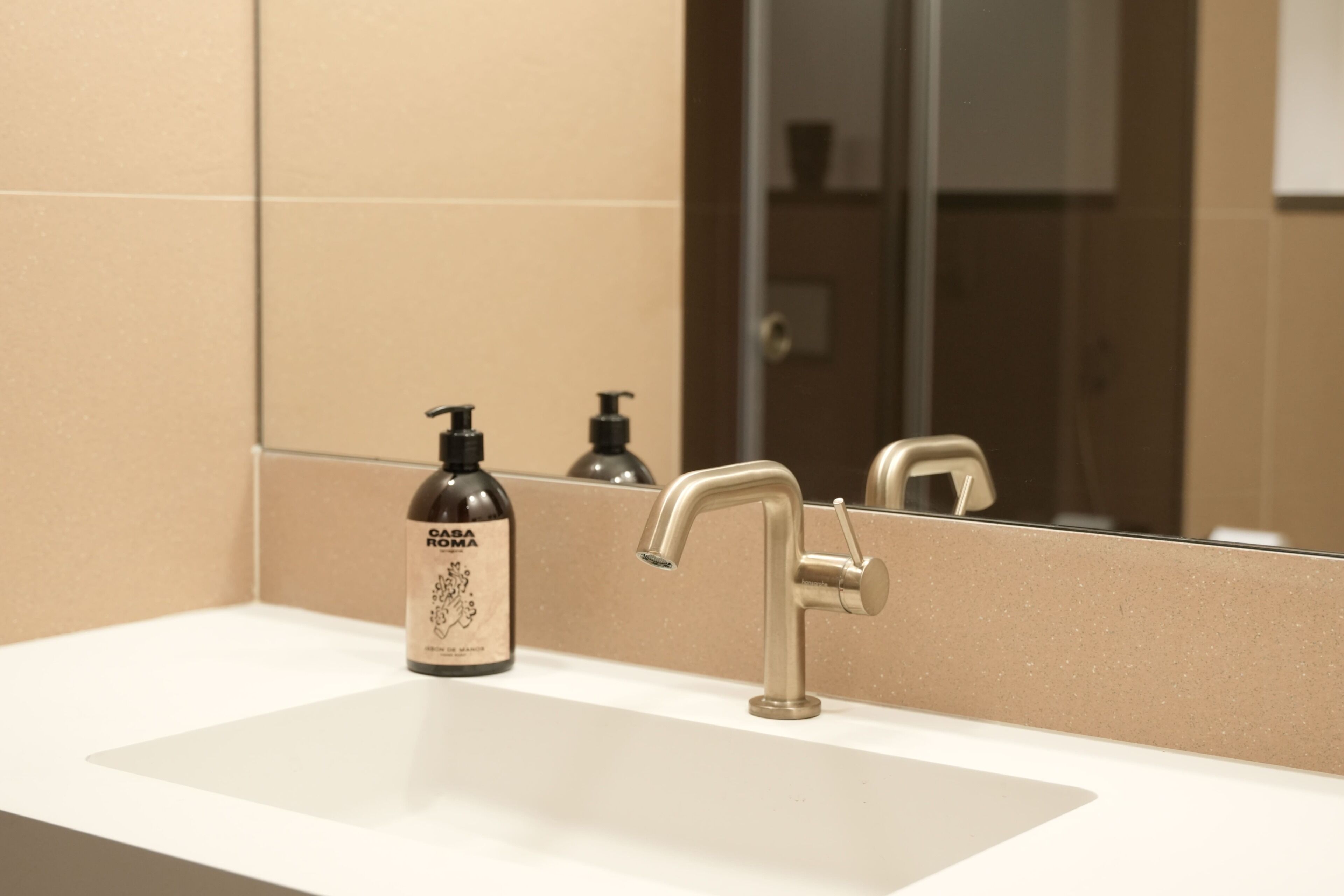 A bathroom with a sink, a mirror, and a bottle of lotion.