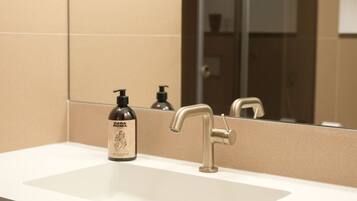 A bathroom with a sink, a mirror, and a bottle of lotion.