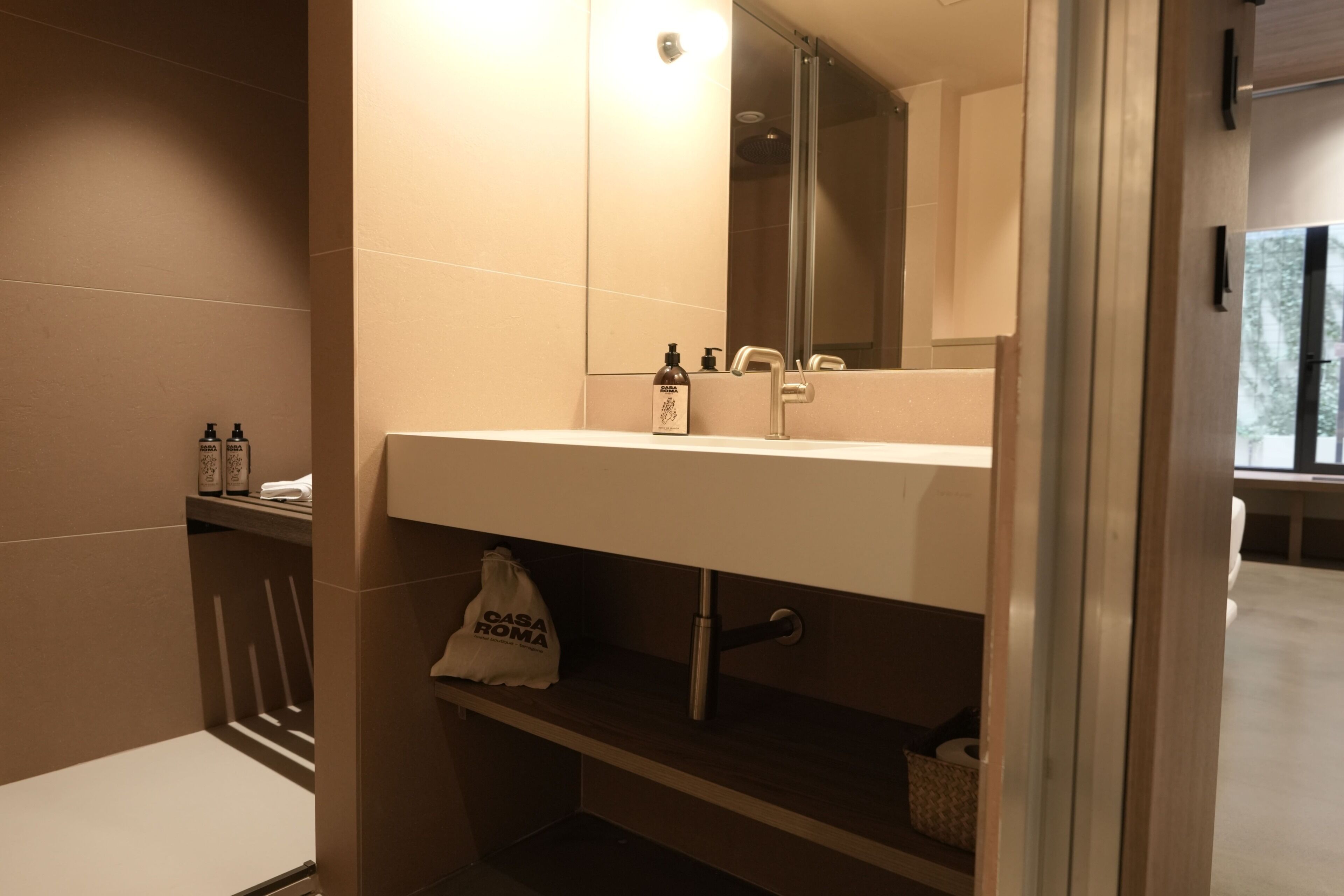 Un baño con lavamanos blanco, un espejo y un perchero para toallas.
