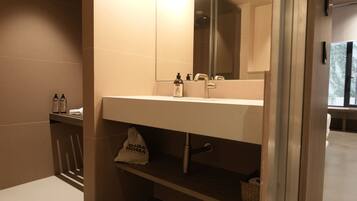 Un baño con lavamanos blanco, un espejo y un perchero para toallas.