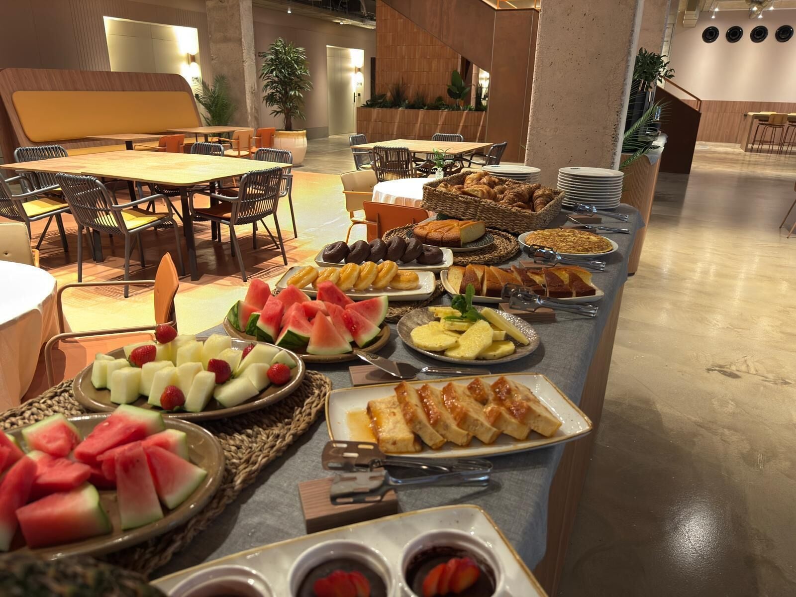 A buffet with various fruits, pastries, and bread.