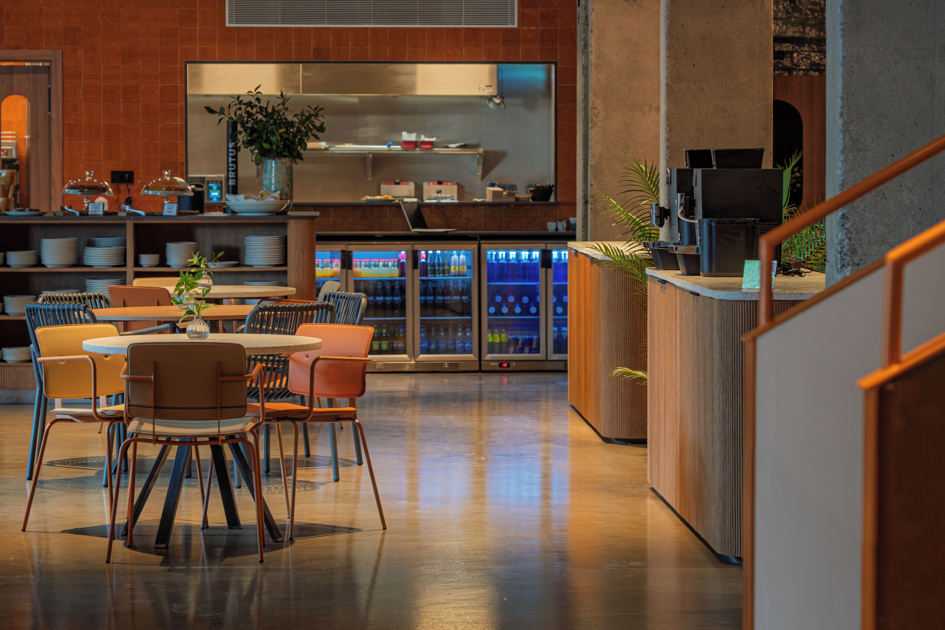 A modern interior with a dining area, kitchen, and beverage dispensers.