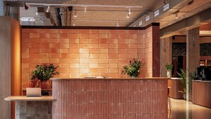 A reception desk with a laptop, potted plants, and a wooden panel wall. - CASA ROMA Hostel Boutique (Tarragona)
