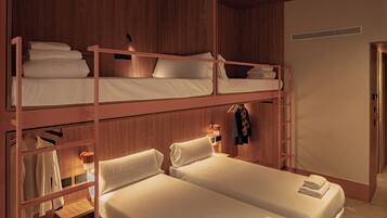 A bunk bed room with a wooden interior, a desk with a lamp, and a wardrobe.