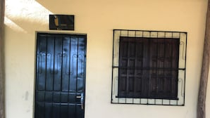 Entrada de un edificio con una reja de metal negra y un ventanal con barrotes.