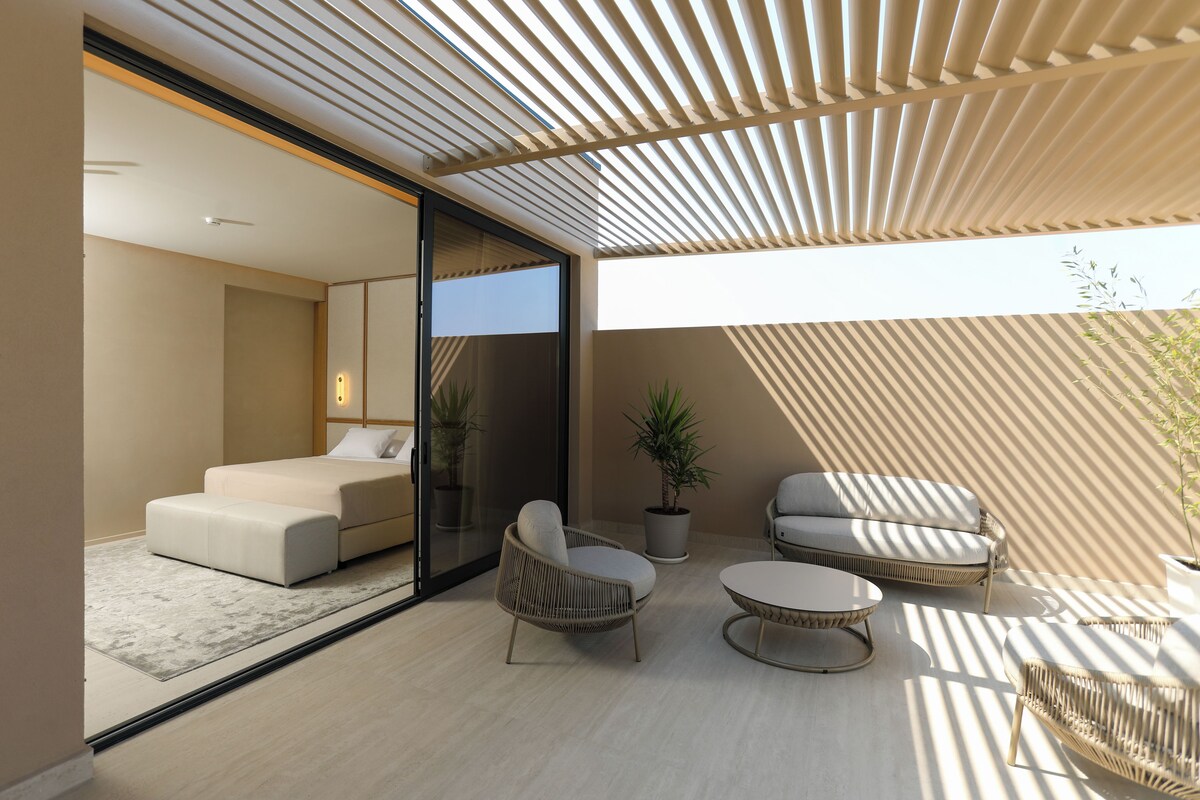 A modern interior with a sofa, two armchairs, a small table, and a potted plant.