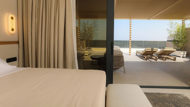 Une chambre d’hôtel moderne dotée d’un grand lit, d’un balcon avec des fauteuils et d’une vue sur la mer.
