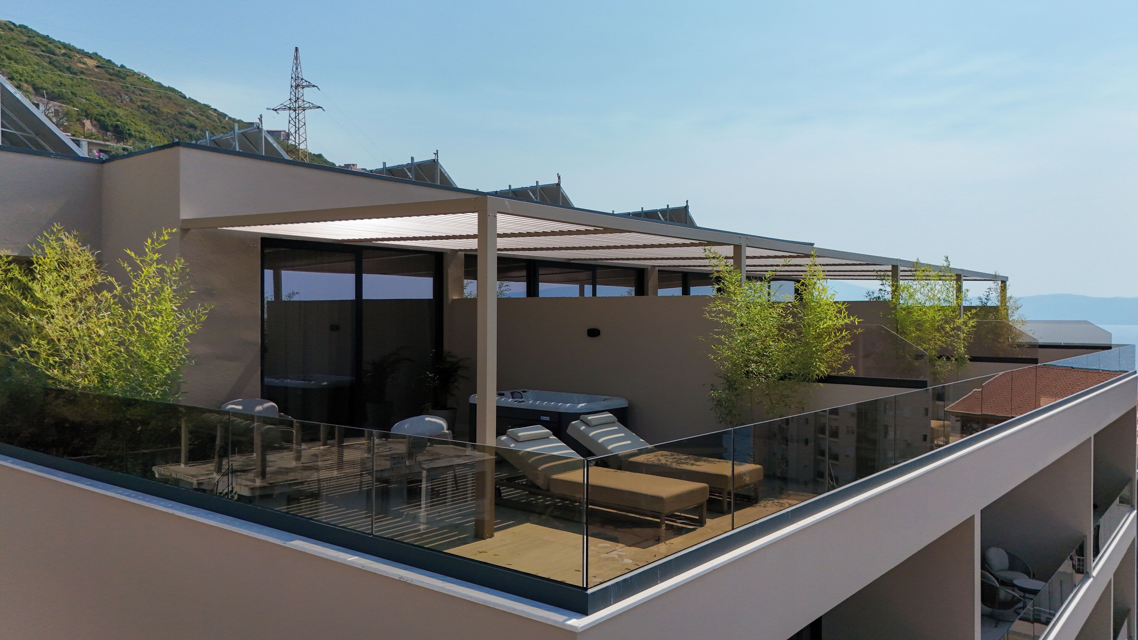 Ein moderner Balkon im Freien mit Glasgeländern, einem Whirlpool und einer Sitzgelegenheit.