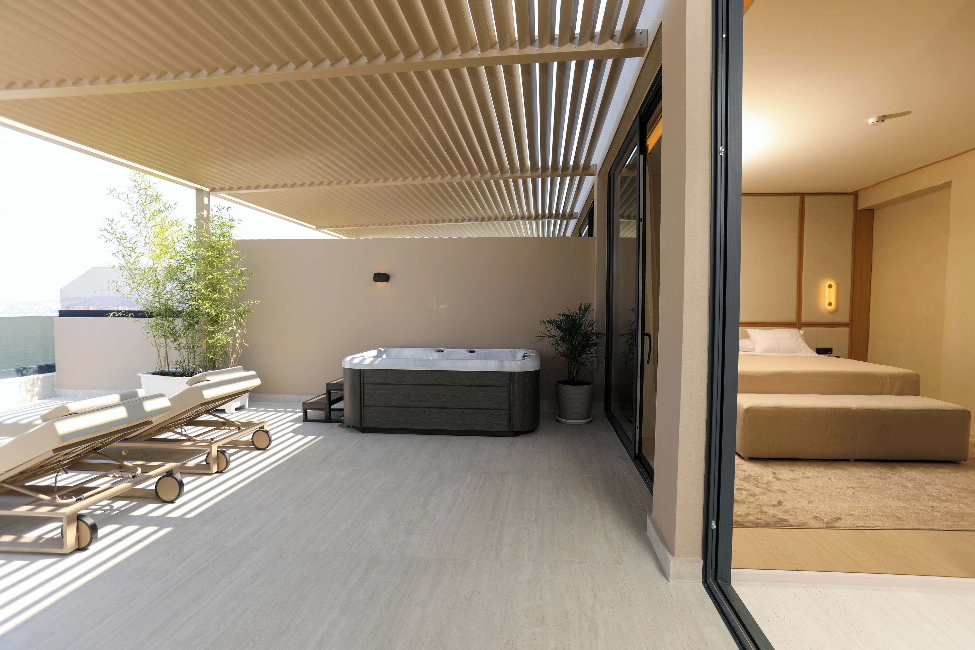 Et moderne hotelværelse med stort vindue, privat balkon med liggestole, jacuzzi og seng.