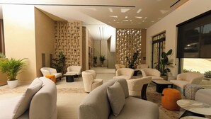 Un salon moderne avec un canapé beige, un mur à motifs et une grande fenêtre.