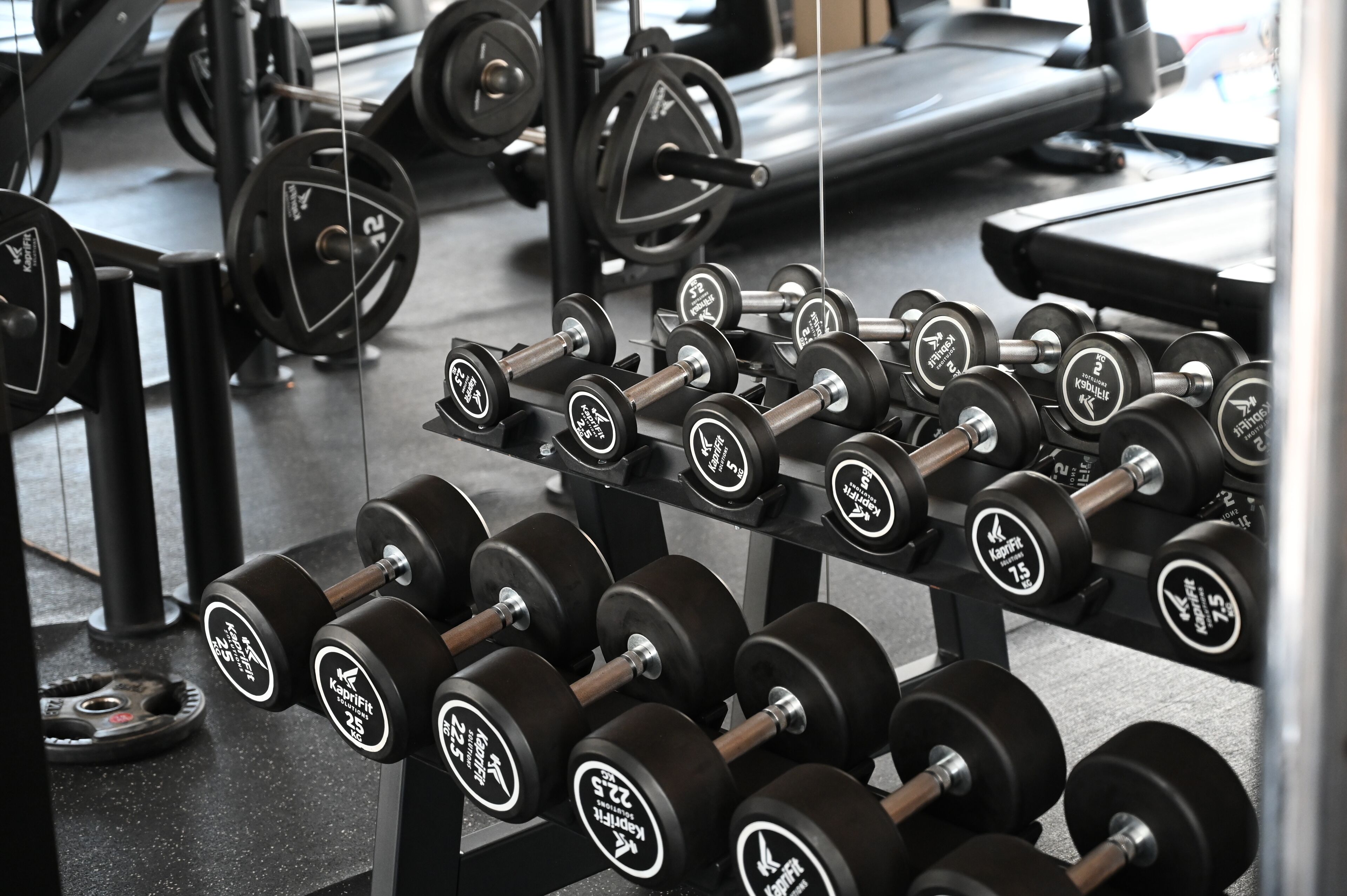 A gym with various weightlifting equipment, including dumbbells and barbells.