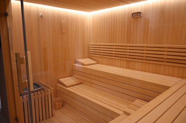 Eine Sauna mit Holzbänken und einer Glastür.