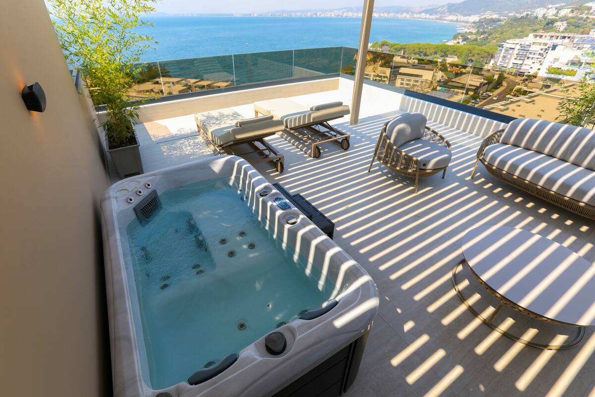 Una terraza en la azotea con jacuzzi, zona de estar y vistas al mar.