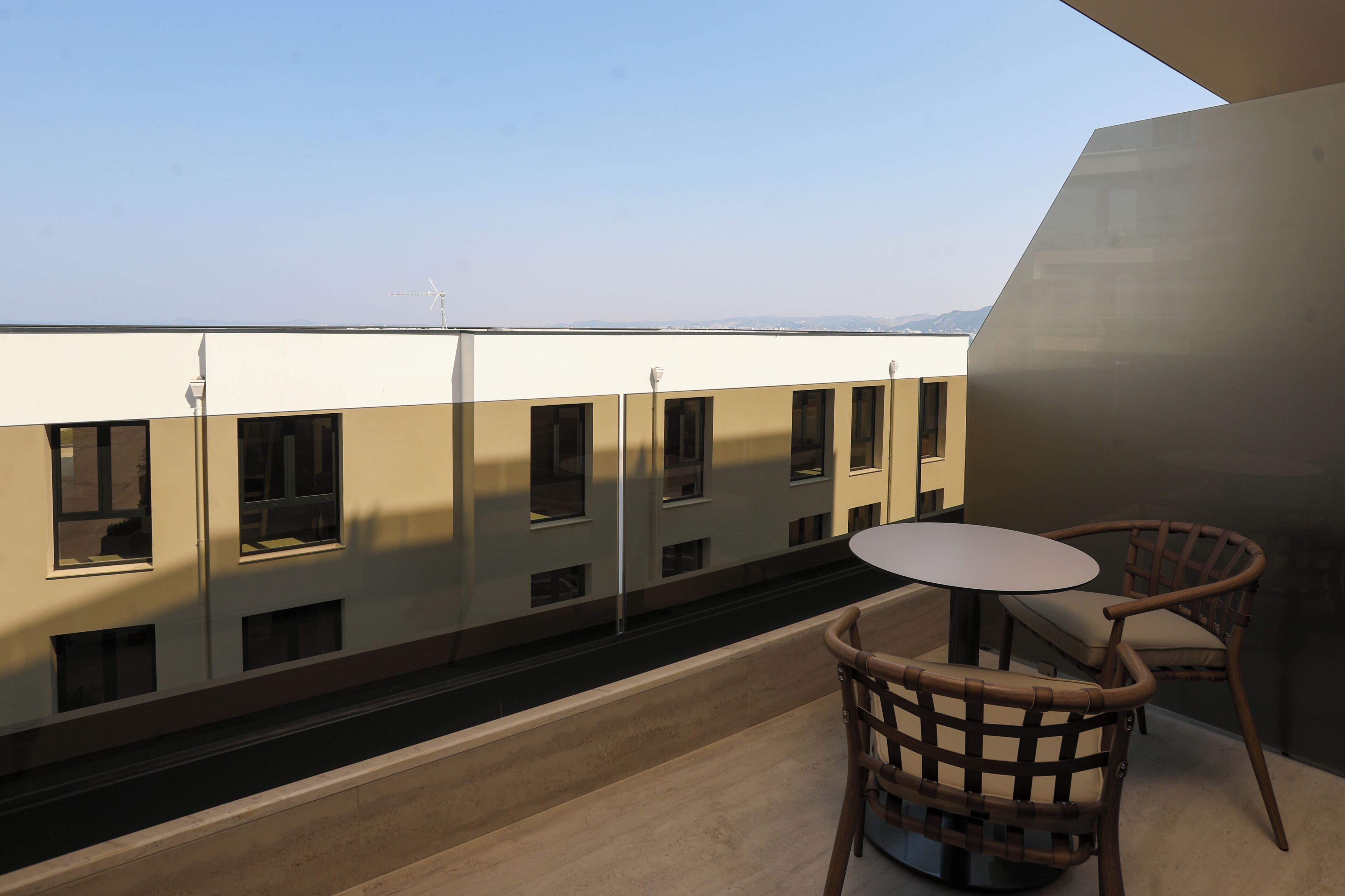 Un balcon donnant sur un immeuble, avec une table et deux chaises.